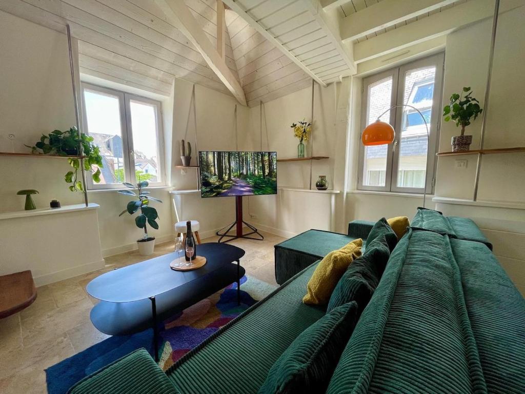 ein Wohnzimmer mit einer grünen Couch und einem Tisch in der Unterkunft La Parent'eizh plein centre-ville 2p in Auray