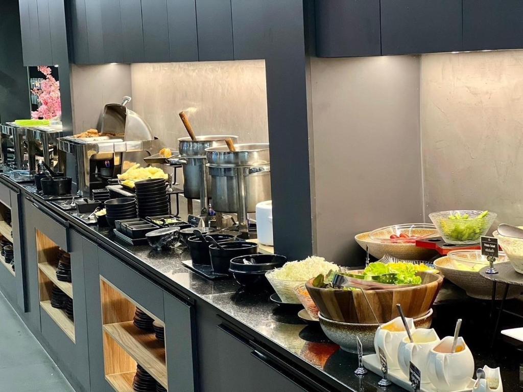 A long buffet counter displaying hot dishes, bowls, salads and condiments.