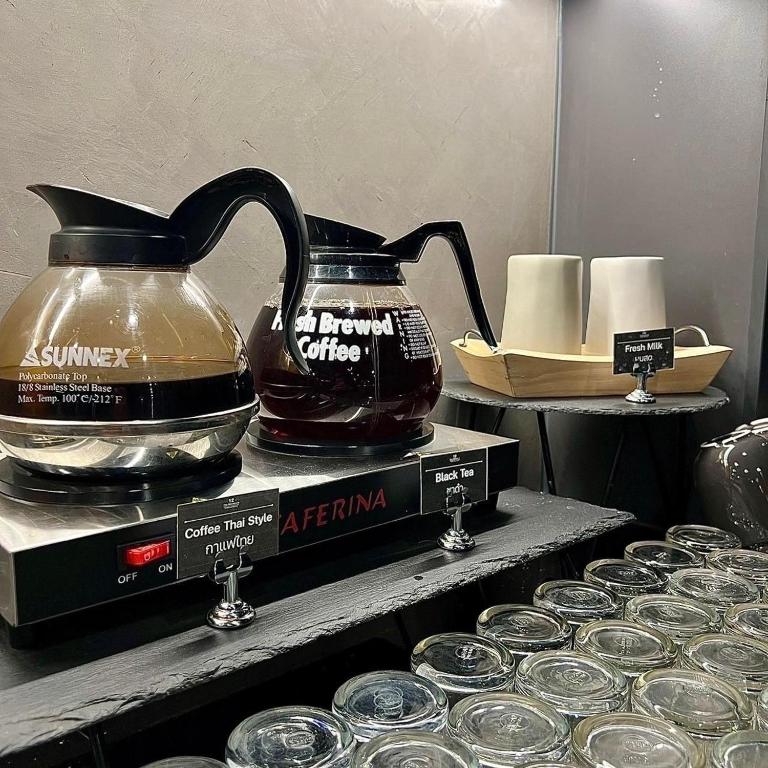A self-service coffee and tea station with hot-water equipment and cups.