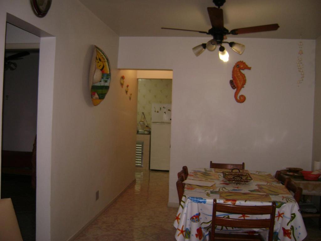 a dining room with a table and a ceiling fan at Apartamento Temporada Enseada in Guarujá