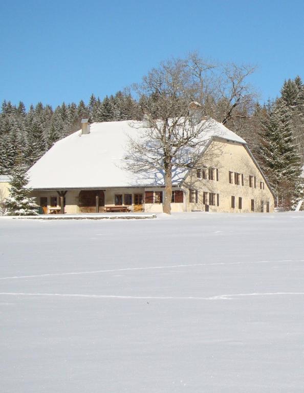 a barn with a snow covered roof in a field at L'Annexe Apparthôtel du Haut-Doubs, 4 étoiles in Les Hôpitaux-Vieux
