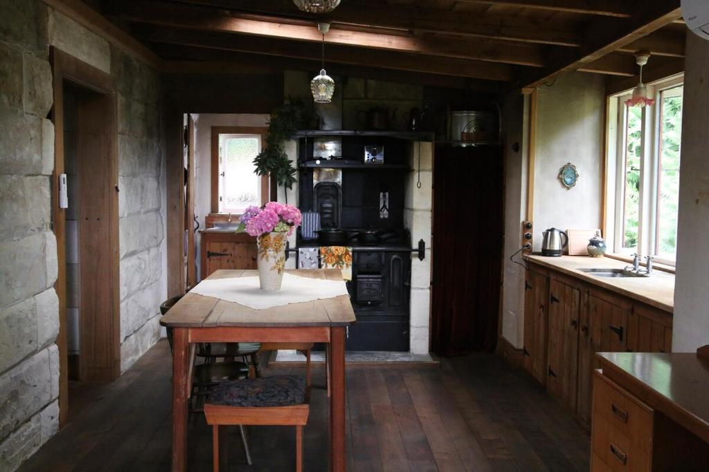 a kitchen with a table with a vase of flowers on it at Granny Grunkes Cottage in Oamaru