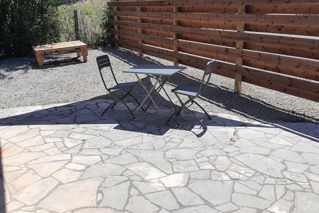 d'une table, de deux chaises et d'un banc sur une terrasse. dans l'établissement Grand T2 tout confort au calme avec terrasse, à Lagarrigue