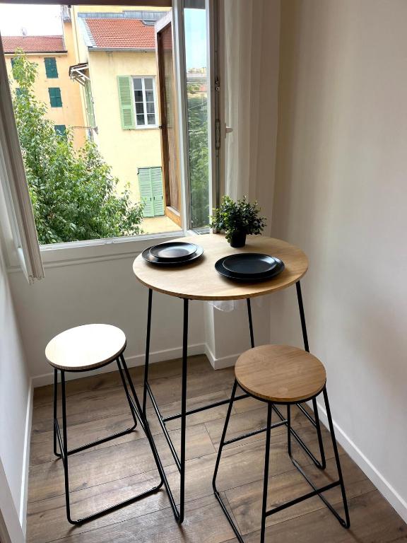 une table et deux tabourets devant une fenêtre dans l'établissement Festival Park Luxe Studio, à Menton