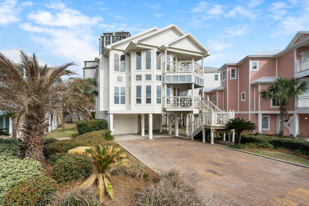 a large white house with a balcony and palm trees at Calypso Breeze in Gulf Shores