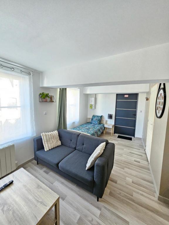 - un salon avec un canapé bleu et un lit dans l'établissement Studio cosy à 5min à pieds de la gare, à Valenciennes
