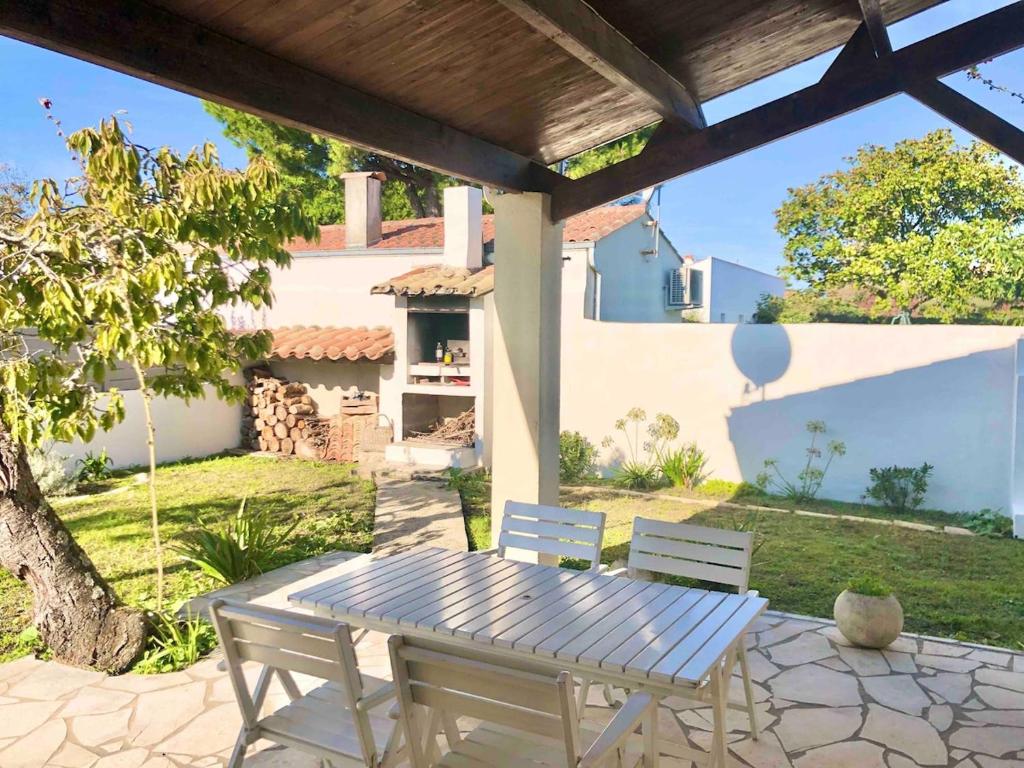 a picnic table and two chairs on a patio at Maison familiale 3 chambres proche de la plage, jardin & tranquillité in Saint-Denis-dʼOléron