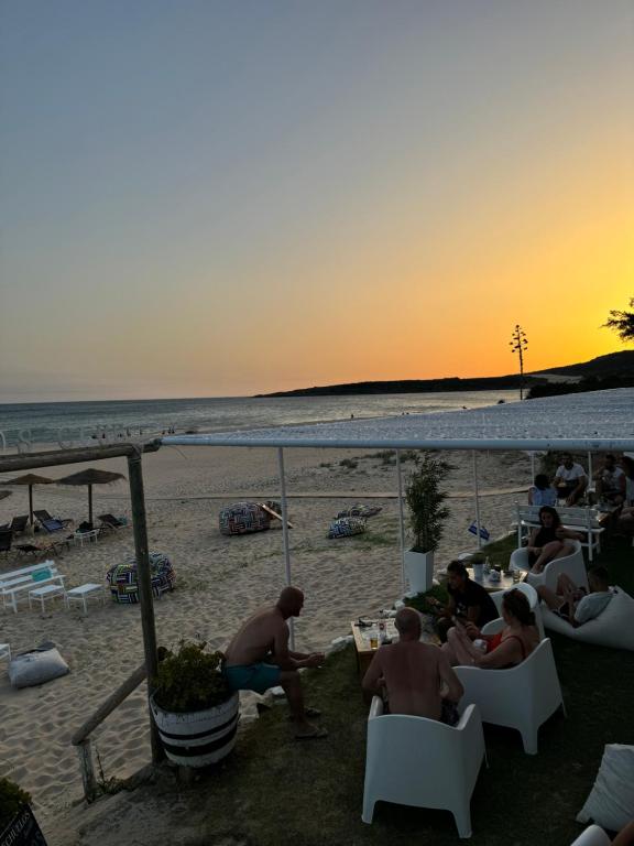 a group of people sitting on the beach at sunset at Hostal Rios in Bolonia