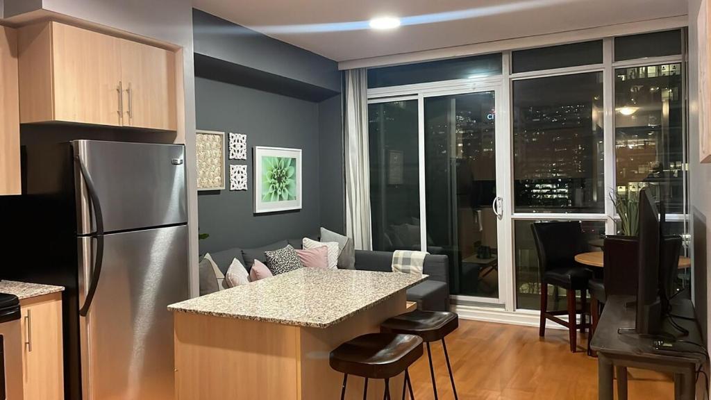 a kitchen with a stainless steel refrigerator and a living room at 1 BD and Den at Scotiabank Arena in Toronto