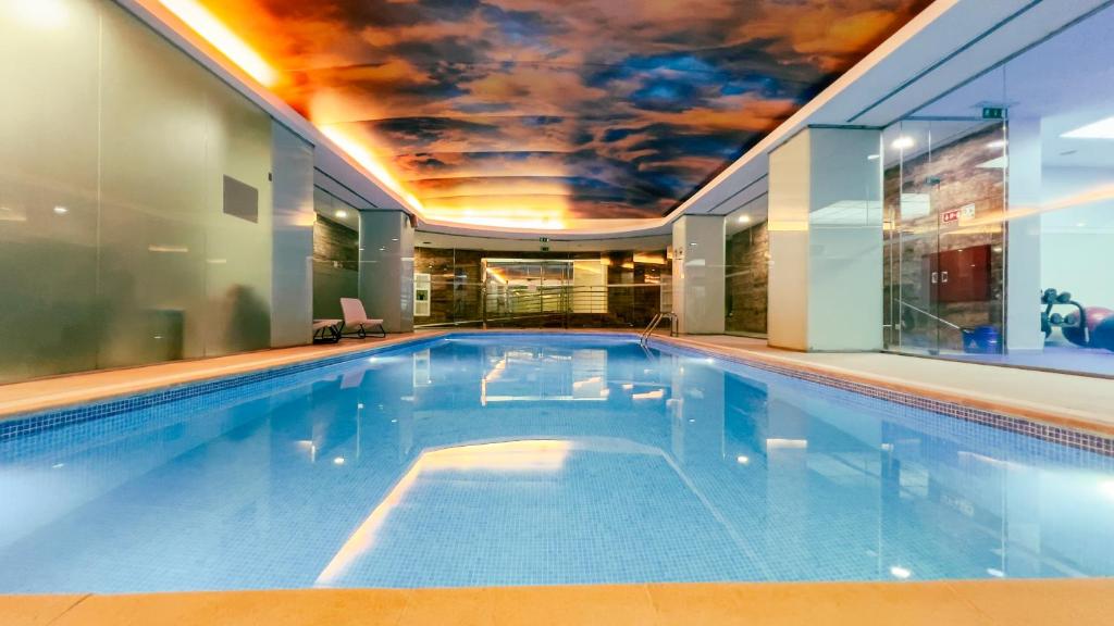 an indoor swimming pool with a ceiling covered in a mural at VIP Executive Entrecampos Hotel & Conference in Lisbon