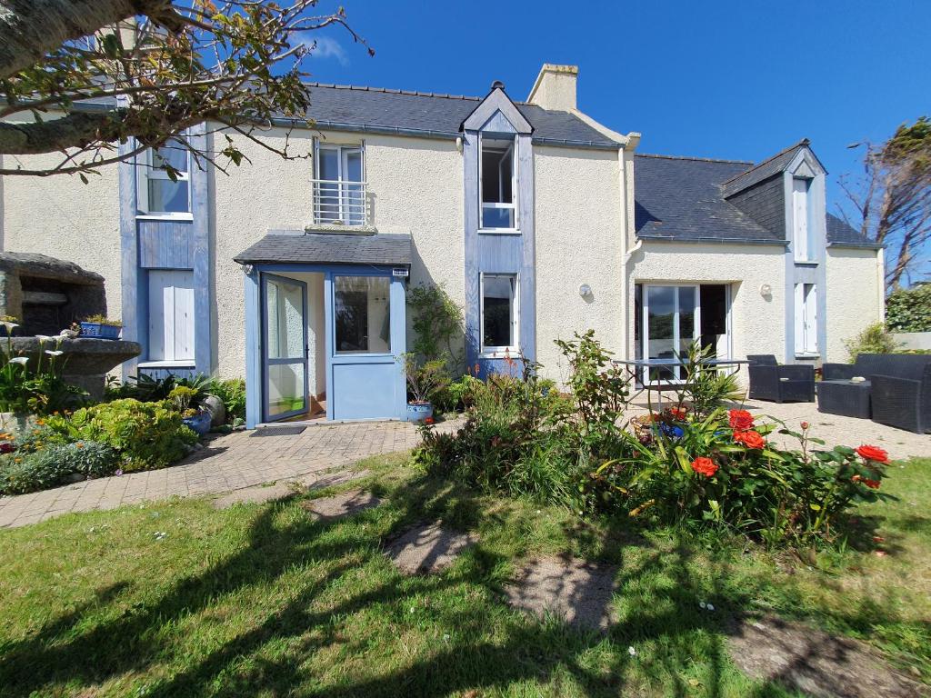 une maison avec une porte bleue et des fleurs dans l'établissement Jolie maison vue mer 6 personnes à Plouguerneau, à Plouguerneau