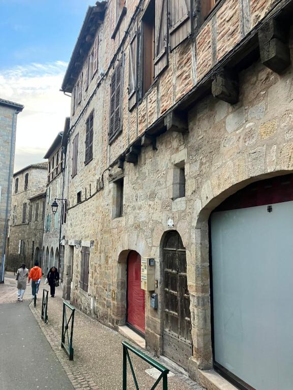a stone building with a red door and people walking down a street at Paloma in Figeac
