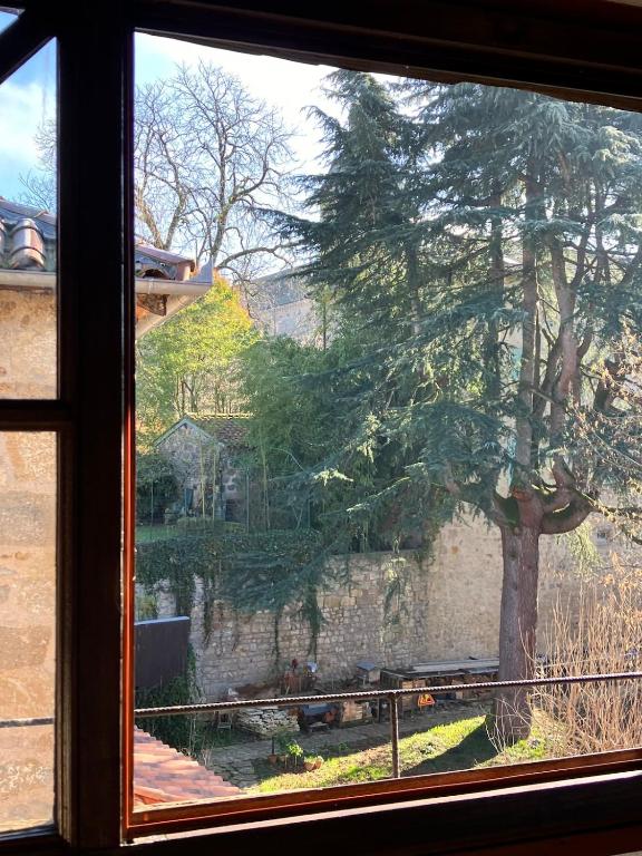 a window view of a tree and a stone wall at Paloma in Figeac