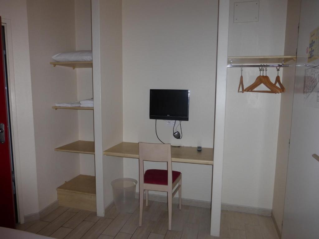 a room with a desk with a tv and a chair at La Godinière in Cholet