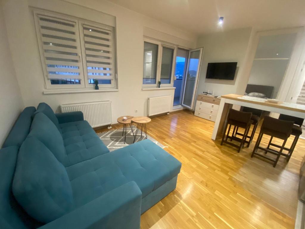 a living room with a blue couch and a kitchen at Astra apartman BL in Banja Luka
