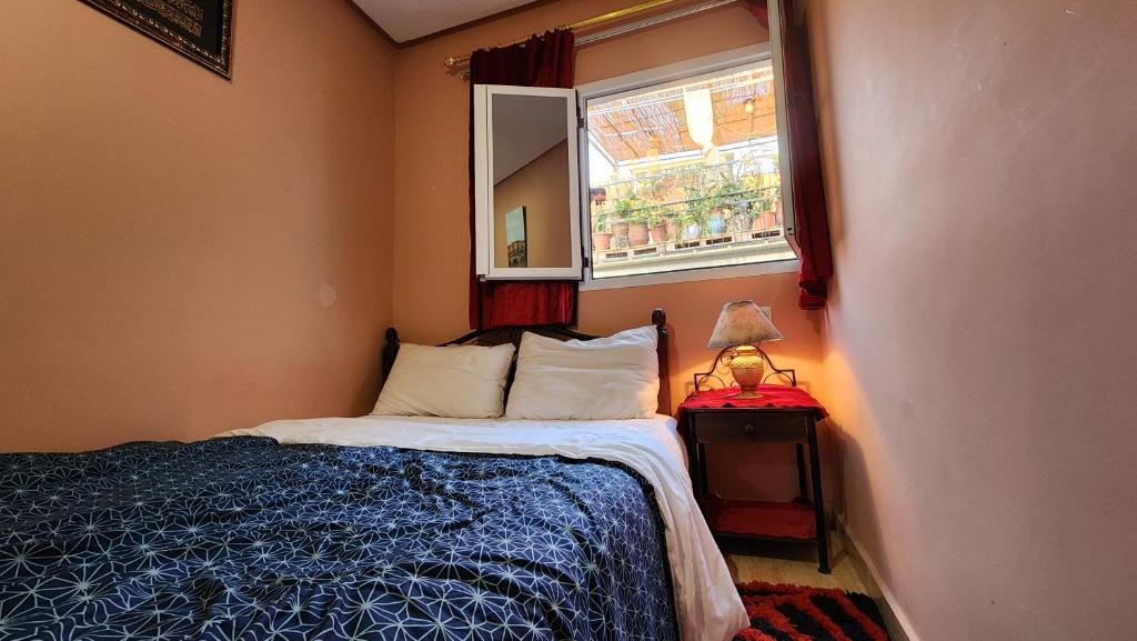 a small bedroom with a bed and a window at Quadra Sphere rooftop in Tamraght Ouzdar