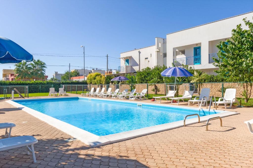 a swimming pool with lounge chairs and umbrellas at Beach Life Apartment In Boncore in Torre Lapillo