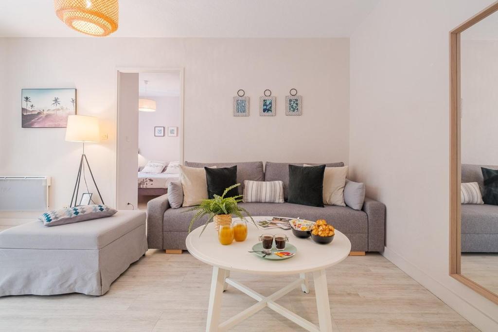 a living room with a couch and a table at Les Capitouls - avec entrée autonome, clim neuve, jardin, parking privé & sa piscine ! - in Toulouse