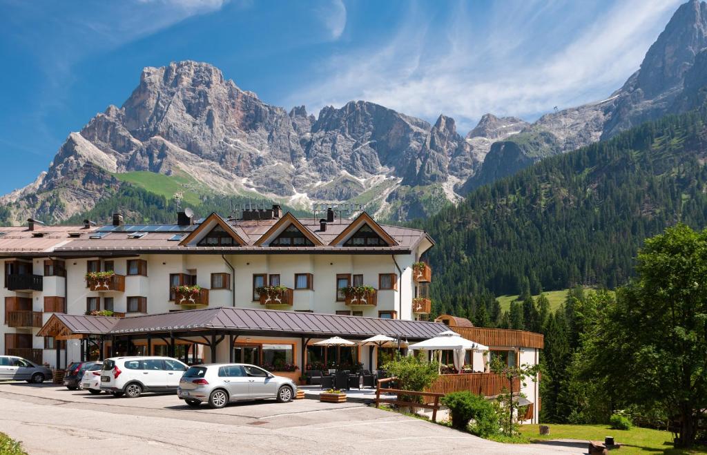 a hotel with cars parked in front of a mountain at Hotel Europa in San Martino di Castrozza