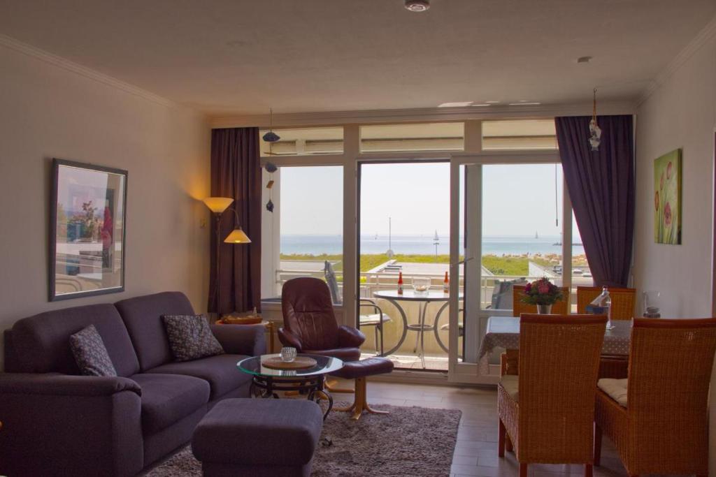 - un salon avec un canapé et une chambre avec vue dans l'établissement Inselblume 75 - Gemütliche Ferienwohnung mit Balkon und Meerblick, à Burgtiefe auf Fehmarn 