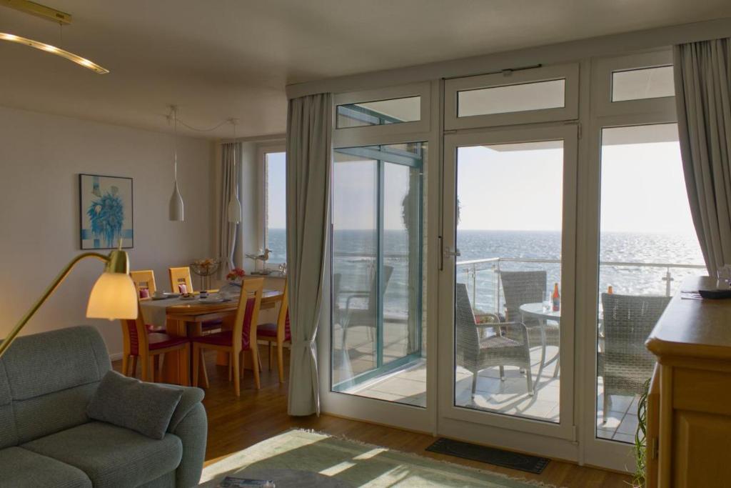 a living room with sliding glass doors with a view of the ocean at Inselblume 16 - Ferienwohnung mit Meerblick in der Strandburg B2.6 in Burgtiefe auf Fehmarn 