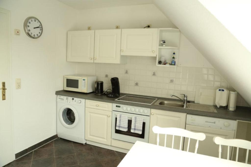 une cuisine blanche avec un évier et un micro-ondes dans l'établissement Inselblume 34 - Ferienwohnung mit Loggia, à Burg