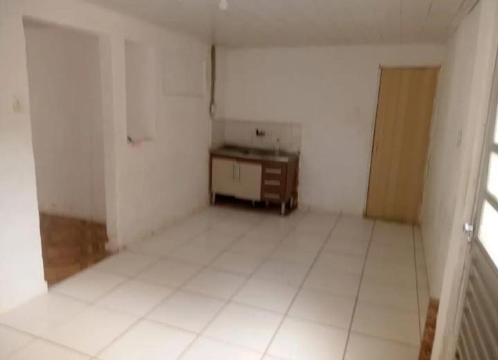 an empty room with a white floor and a table at Casa para alugar temporária in Maceió