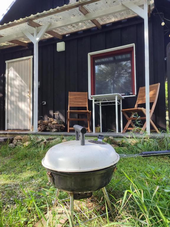 a grill in the grass in front of a house at Self Check-in Sauna Cabin next to Hiking Trails in Kärde