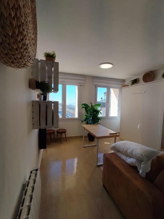 Una sala de estar con una cama y una mesa y ventanas. en MIRAMAR con vistas, en Sierra Nevada