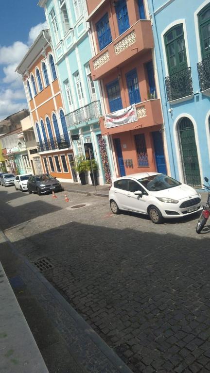 una macchina bianca parcheggiata di fronte ad alcuni edifici di Casarão santo Antônio a Salvador