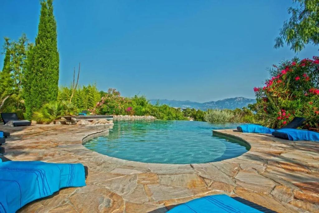 a swimming pool with blue loungers in a backyard at Charmante Maison de Vacances à Olmeto avec Piscine in Olmeto