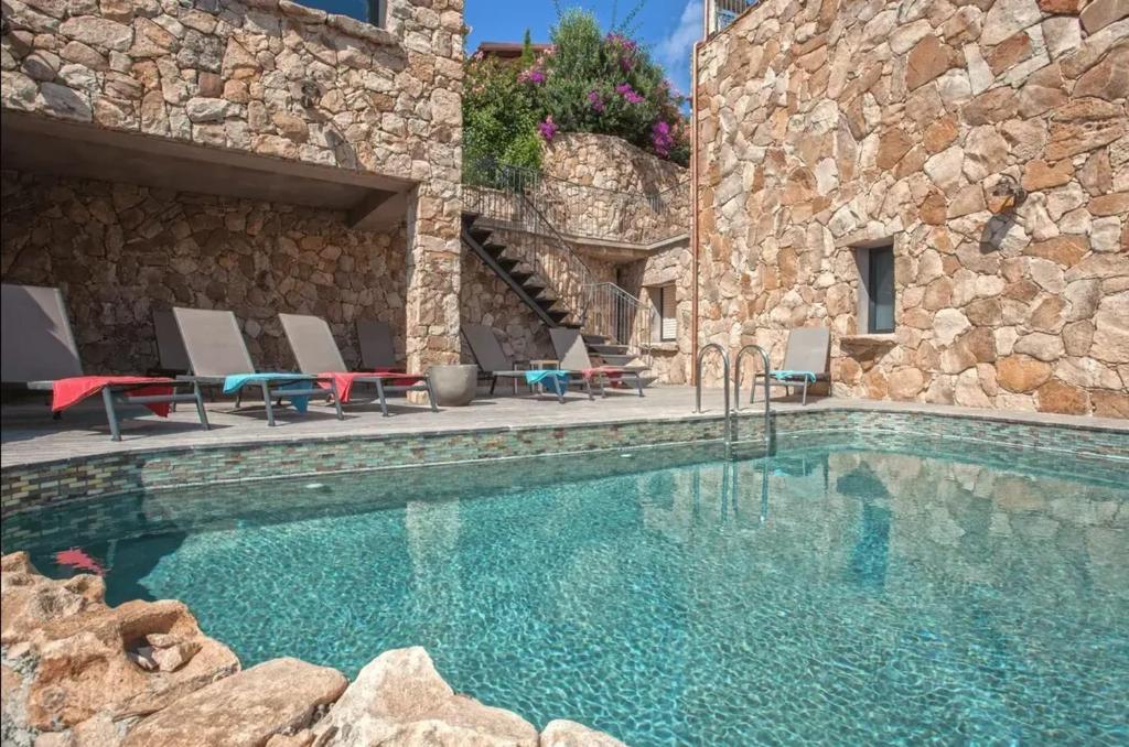 a swimming pool in front of a stone building at Appartement avec vue sur la mer à Olmeto in Olmeto