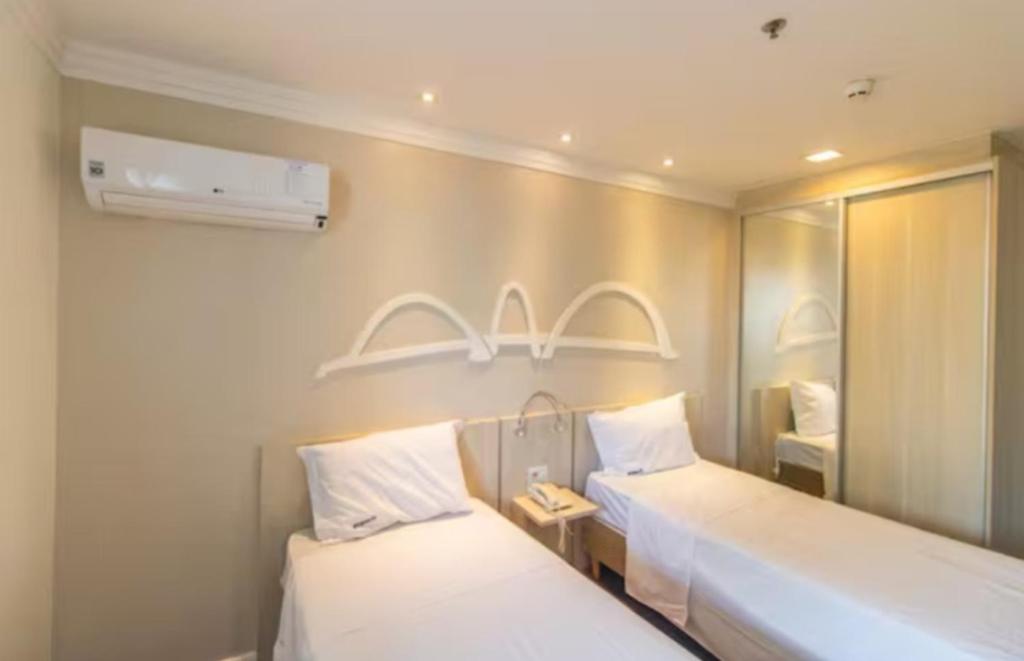 - 2 lits dans une chambre avec un miroir et une chambre dans l'établissement Hotel Mercure, à Brasilia