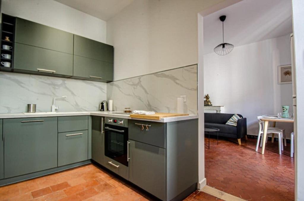 une cuisine avec des placards verts et un salon dans l'établissement Casamea - Famille, 2 chambres, Centre , Calme, à Ajaccio