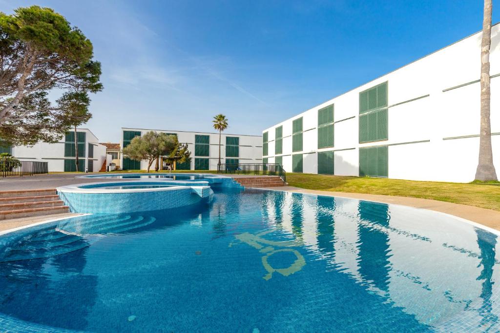 a large swimming pool in front of a building at Apartamento Cala´n Bosch 1a Planta in Cala en Bosc
