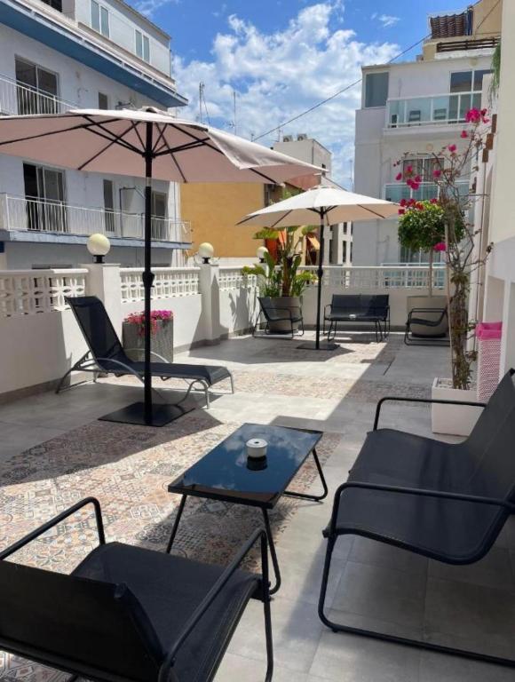 a patio with chairs and tables and an umbrella at Olivia Apartments TRG in Benidorm