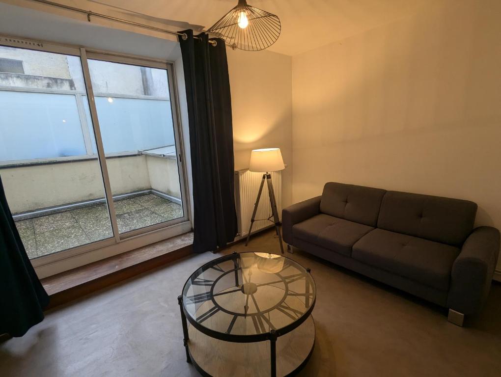 un salon avec un canapé et une table en verre dans l'établissement Appartement tout équipé de 2 chambres a charmes, à Charmes