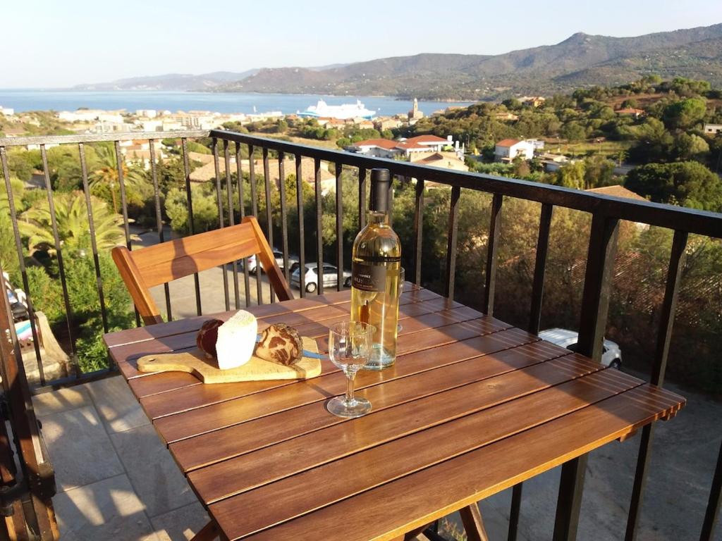 - une table en bois avec une bouteille de vin et un verre dans l'établissement La Perle du Valinco #Familial#Balcon#Piscine#Mer, à Propriano
