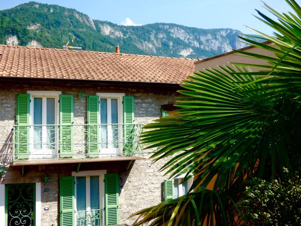 a building with green shuttered windows and a palm tree at Casa Contrada Bella in Varenna