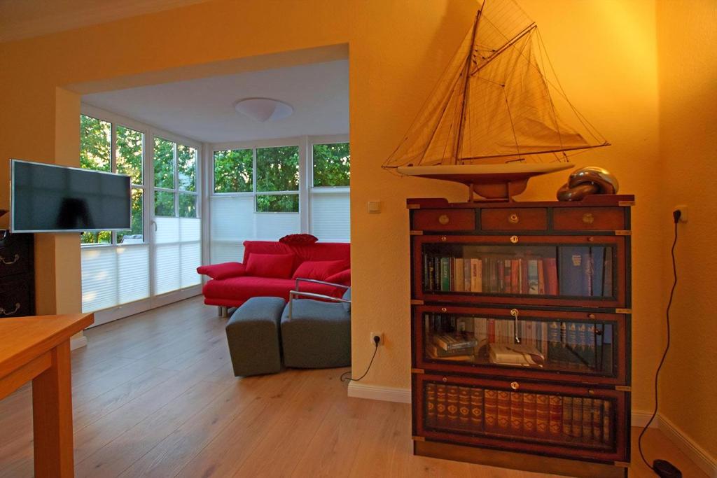 ein Wohnzimmer mit einer roten Couch und einem Bücherregal in der Unterkunft Maisonette Seegang - eingezäuntes Grundstück mit Seeblick in Flessenow