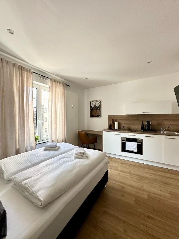 a bedroom with a large bed and a kitchen at Spiritus Apartments in Augsburg