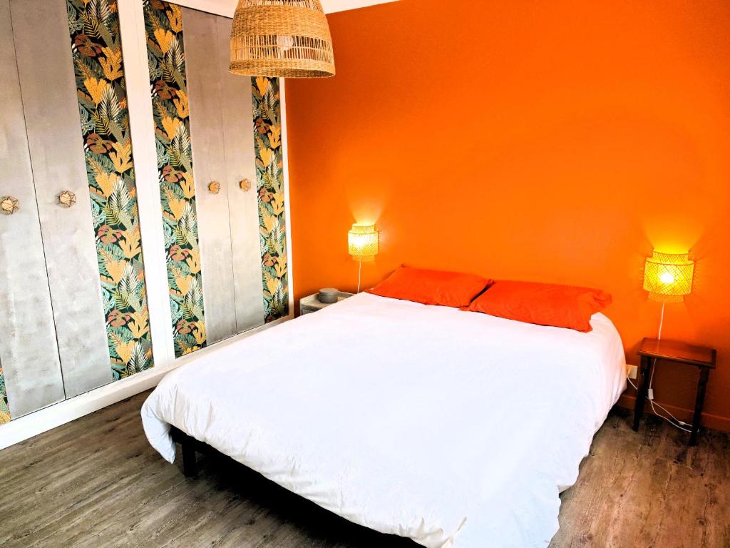 une chambre avec un lit blanc avec un mur orange dans l'établissement ESCALE Appartement 4 pers, à Les Sables-dʼOlonne