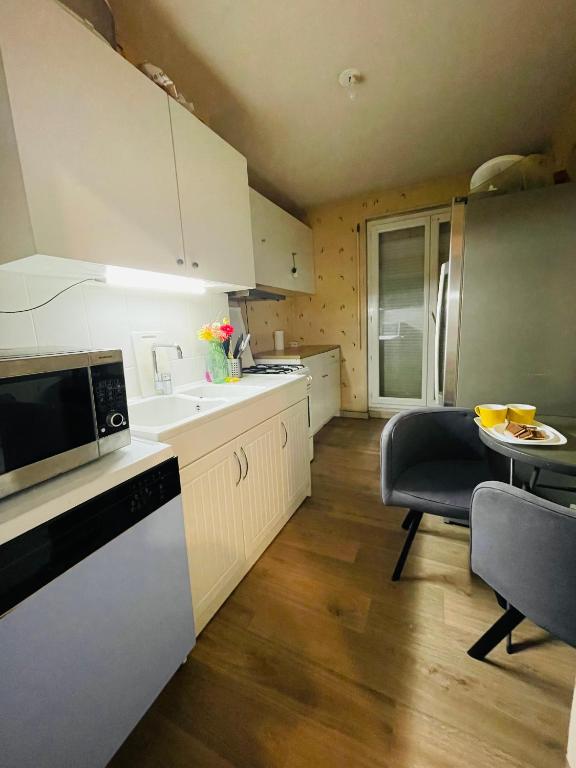 une cuisine avec des armoires blanches, une table et un micro-ondes dans l'établissement Hébergement confortable, à Rennes