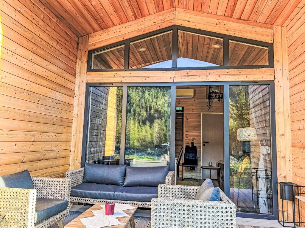 eine abgeschirmte Veranda mit Sofa und Stühlen in der Unterkunft Holiday Home Tiny Haus Glockenalm-Haus Hakuna Matata by Interhome in Aurach