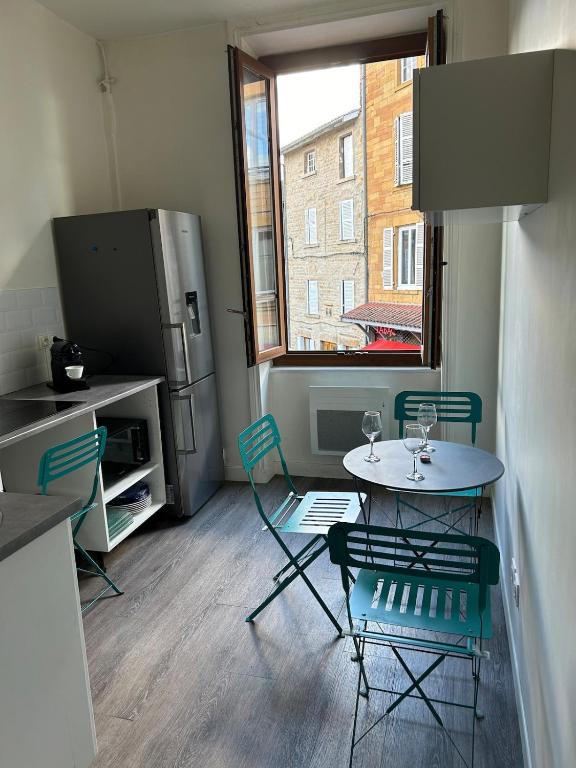 une petite cuisine avec une table et des chaises ainsi qu'une fenêtre dans l'établissement Appartement cosy, à Chessy