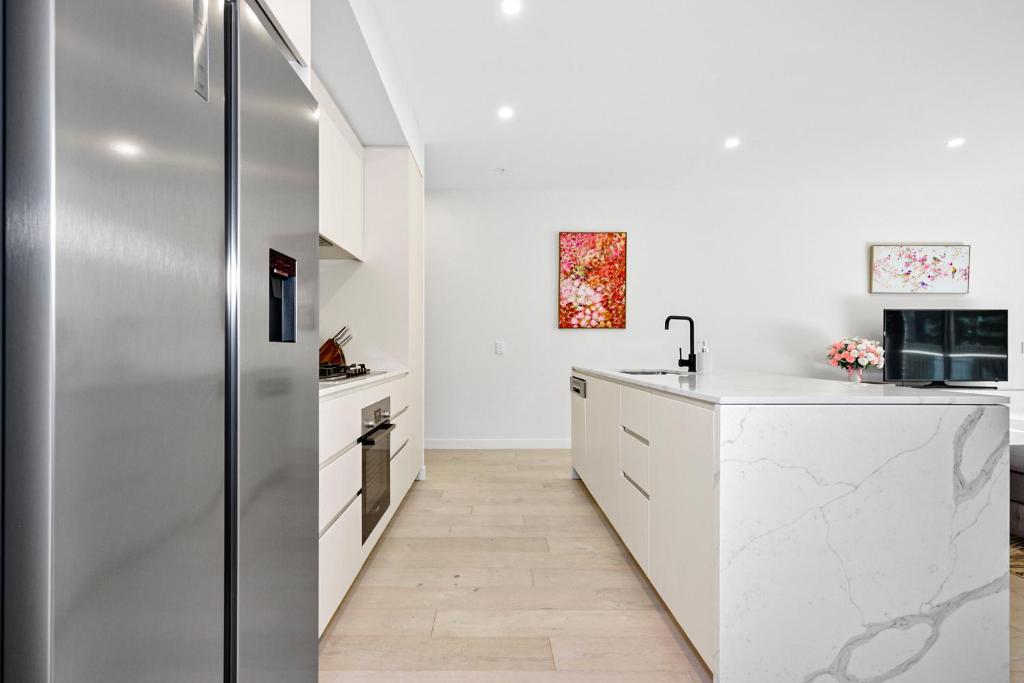 a kitchen with white counters and a refrigerator at Classy Spaces Keysborough - New 2 Storey Townhouse in Keysborough