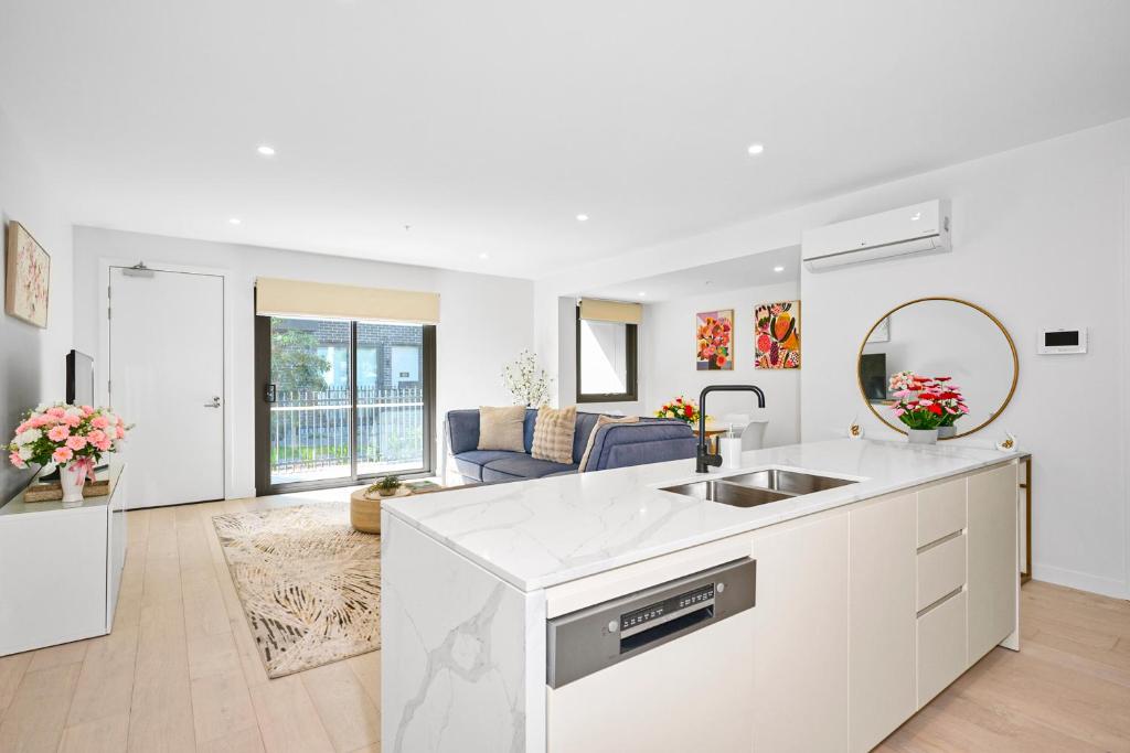 a white kitchen with a sink and a living room at Classy Spaces Keysborough - New 2 Storey Townhouse in Keysborough