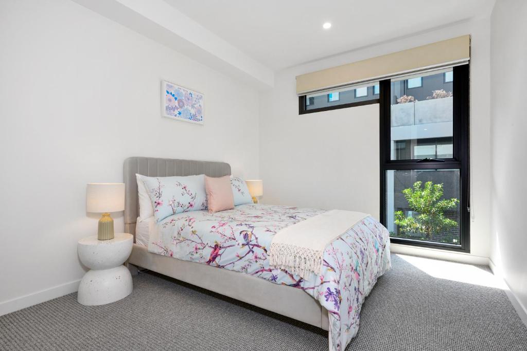 a white bedroom with a bed and a window at Classy Spaces Keysborough - New 2 Storey Townhouse in Keysborough