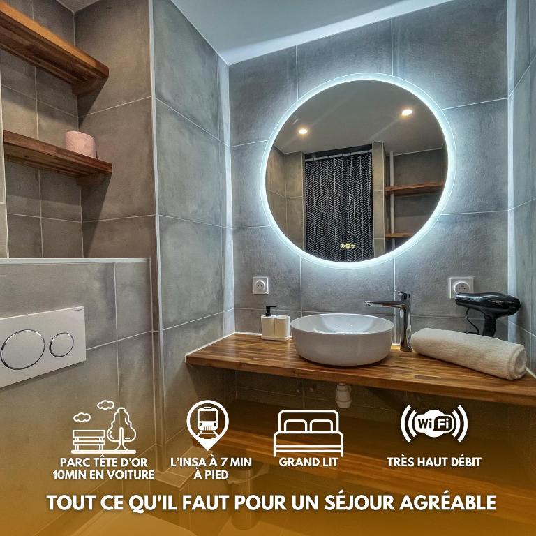 La salle de bains est pourvue d'un miroir rond et d'un lavabo. dans l'établissement Le Céleste, à Villeurbanne