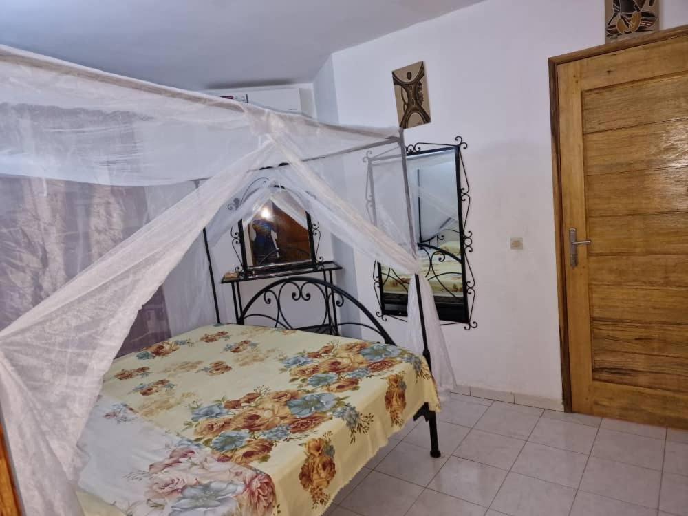 a bedroom with a bed with a mosquito net at Maison 2 chambres dans résidence in Saly Portudal